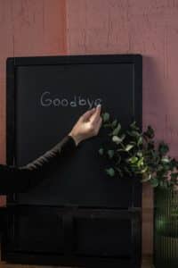 person writing goodbye on a chalkboard